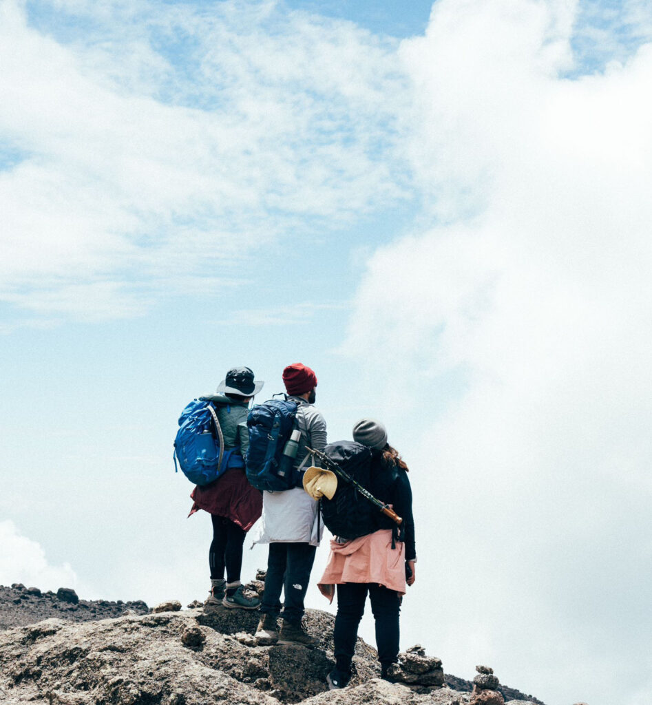 Three people looking at the horizon at the highest point in Africa, Mount Kilimanjaro